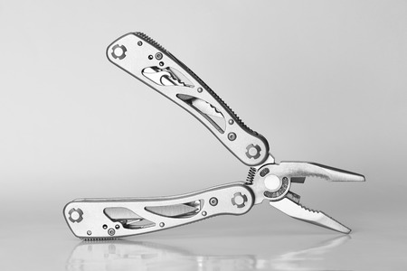 Steel multitool isolated on grey background close up