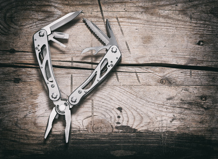 stanless steel multitool on wooden background top view