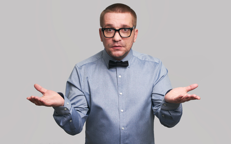 Surprised hipster wearing glasses and bow tie. Shocked casual man Isolated over grey background. People emotions conceptの写真素材
