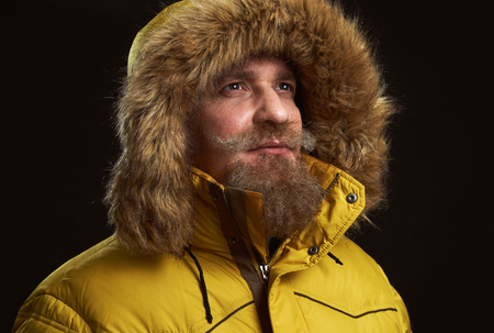 serious bearded man wearing winter clothes. Guy in coat looking up over black backgroundの写真素材