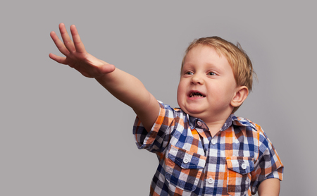 portrait of adorable little happy boy wearing shirt looking aside over grey backgroundの写真素材