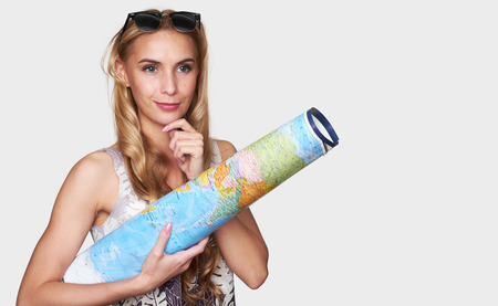 Young beautiful woman wearing sunglasses and holding a world map. Travel or vacation conceptの写真素材