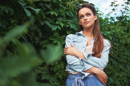 Casual pretty woman walking in the park. Beautiful girl with long brown hair wearing denim jacketの写真素材