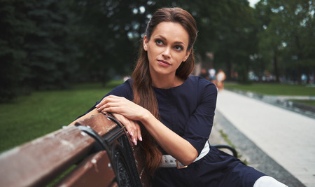 pretty woman sitting on a bench in the park. Cute Girl Outdoors portraitの写真素材