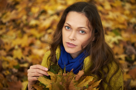 Pretty woman walking in the autumn park. Girl wearing warm clothes. Outdoors portrait