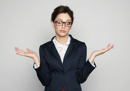 Confused business woman throws up her hands. Isolated on greyの写真素材