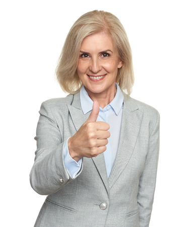 Smiling mature attractive businesswoman showing thumbs up. Isolated on whiteの写真素材