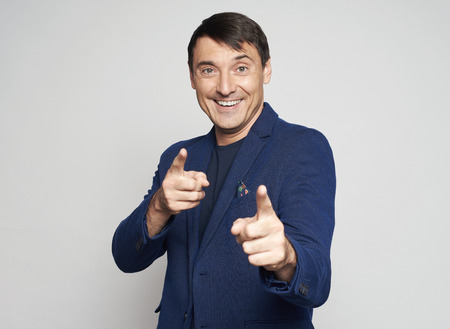Handsome business man pointing finger at you isolated on grey studio backgroundの写真素材