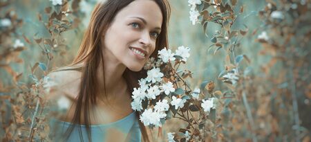 Happy pretty girl is sitting on green grass in the park