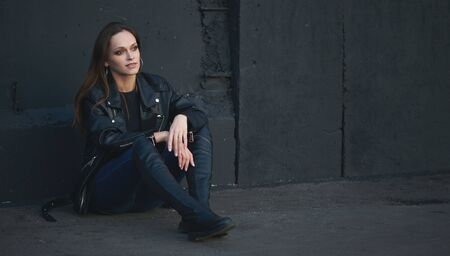 portrait of brunette woman is sitting on a streetの写真素材