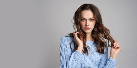Beautiful girl wint long wavy brown hair isolated on grey background with copy space