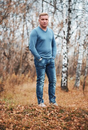 Full length portrait of a casual man in the autumn parkの写真素材