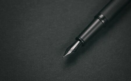 Old fountain pen on a black paper backgroundの写真素材
