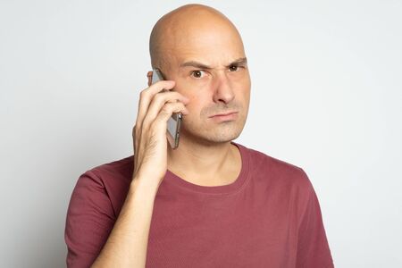 unpleasant man is holding smartphone isolated on grey background