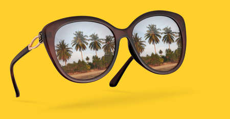 Retro sunglasses with reflection of palms isolated on yellow backgroundの写真素材