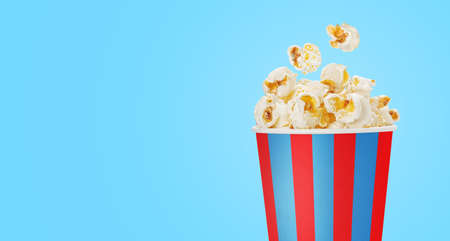 popcorn in a striped cup over blue backgroundの写真素材