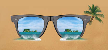 Sunglasses on a sand of tropical beach with sea reflection. Vacation concept.の写真素材