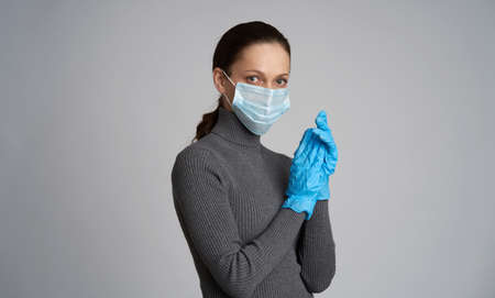 Woman is wearing medical protection gloves isolated on gray backgroundの写真素材