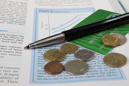 credit card, coins, pen and the economy textbookの写真素材