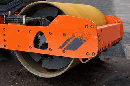 orange steamroller on a pile of wet sand