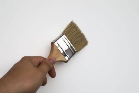hand holding  paintbrush over white backgroundの写真素材