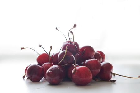 heap of wet sweet cherries on white tableの写真素材