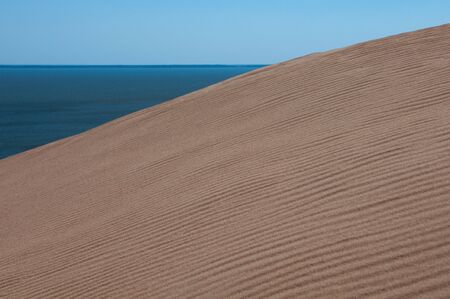 textured dune sand pattern with sky and waterの写真素材