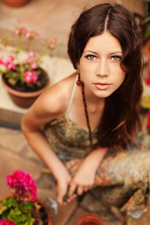 Young girl gardener with long brown hair holding a garden tool and looking at the camera.の写真素材