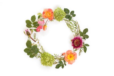 Floral round crown (wreath) with flowers and leaves. Flat lay, top view. Creative arrangement with pink and orange roses, gray grefsheim (spiraea cinerea) leaves, sevenbark (hydrangea arborescens) and nymphaea waterlily.の写真素材