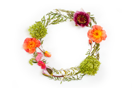 Floral round crown (wreath) with flowers and leaves. Flat lay, top view. Creative arrangement with pink and orange roses, gray grefsheim (spiraea cinerea) leaves, sevenbark (hydrangea arborescens) and nymphaea waterlily.の写真素材