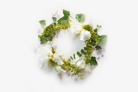 Wedding concept. Floral frame with Iris white flowers, buds, green ivy branches, yellow leaves and small purple flowers isolated on white background. Top view. Flat lay.の写真素材