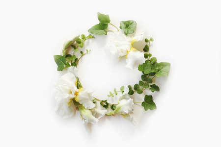 Wedding concept. Fresh Iris white flowers, buds and green ivy branches on white background. Flat lay, top view.の写真素材