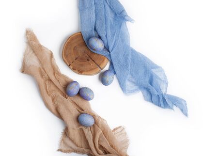 Easter blue eggs on white background with pastel color textile and tree slice. Flat lay. の写真素材