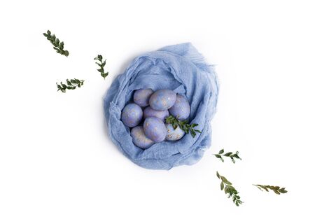Creative nest made of pastel colored textile with blue dyed eggs and green branches. Easter flat lay concept.の写真素材