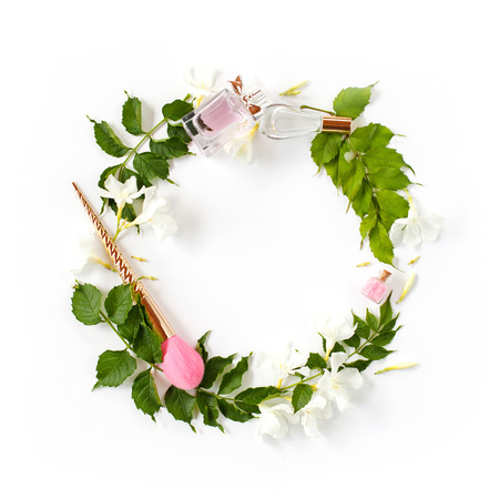 Flowers and beauty accessories composition. Wreath made of bright green leaves, white flowers, perfume, cosmetic brush, bath salt on white background. Spring, summer, beauty blog concept. Flat lay, top viewの写真素材