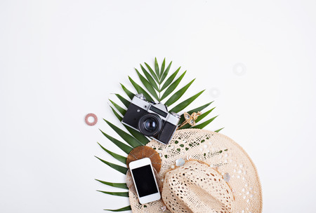 Palm leaves, straw hat and photo camera isolated on white background. Flat lay feminine accessories concept.の写真素材