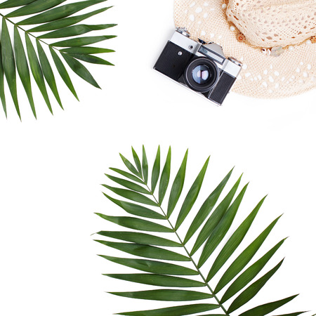 Palm leaves, straw hat and photo camera isolated on white background. Flat lay travel concept.の写真素材