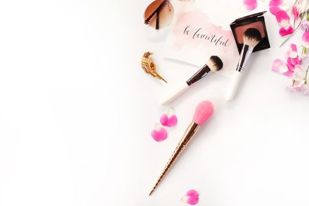 Top view of cosmetics and female accessories on white with pink petals and inspirational words written in calligraphy style `Be beautiful`. Beauty blog flat lay concept.の写真素材