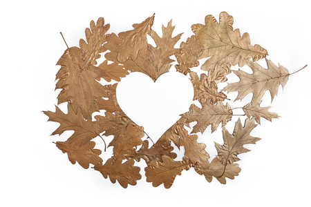 Falling golden metallic leaves on white background with heart. Valentine`s day concept. Flat lay.の写真素材