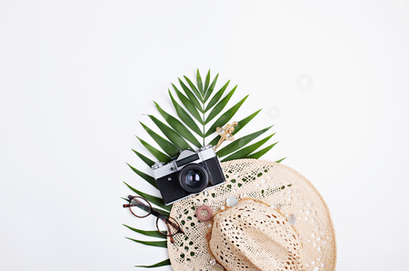 Palm leaves, straw hat and photo camera isolated on white background. Flat lay feminine accessories concept.の写真素材