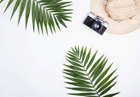 Flat lay traveler accessories on white background with blank space for text. Palm leaves, straw hat and photo camera isolated.の写真素材