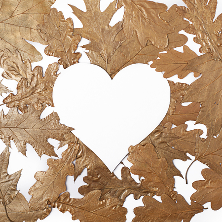White heart on creative arrangement of golden metallic leaves. Valentine`s day concept. Flat lay.の写真素材