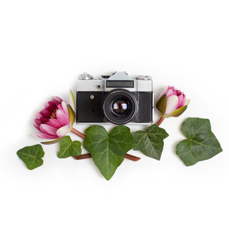 Vintage retro photo camera, dogwood green leaves (cornus alba) and nymphaea waterlily purple flowers on white background. flat lay, top view.の写真素材