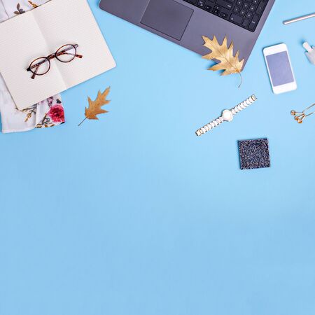 Home office workspace with laptop, glasses and dress on blue background. Fashion blogger work concept. Flat layの写真素材