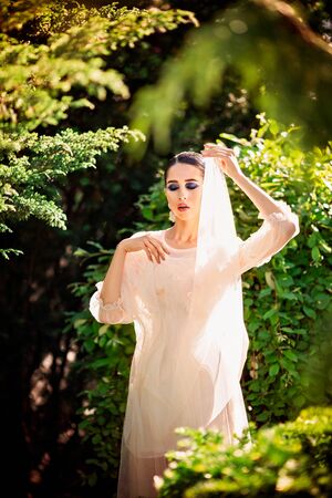 Beautiful lady in sunlight garden. Dreamy portrait of young woman in vintage dress. Beauty fairy-tail wedding concept.の写真素材