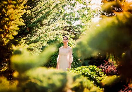 Beautiful lady in sunlight garden. Dreamy portrait of young woman in vintage dress. Beauty fairy-tail wedding concept.の写真素材
