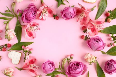 Frame of pink rose flowers, branches, leaves and heart shaped cookies with space for text on background. Flat lay, top view. Romantic concept.の写真素材