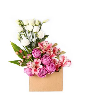 Colorful flowers and green leaves in craft envelope. Floral composition flat lay on white background.の写真素材