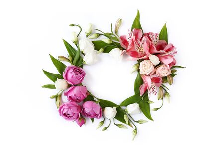 Round floral frame wreath made of rose buds, lily flowers and green leaves isolated on white background. Flat lay, top view.の写真素材