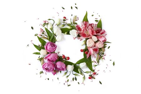 Round floral frame wreath made of rose buds, lily flowers and green leaves isolated on white background. Flat lay, top view.の写真素材